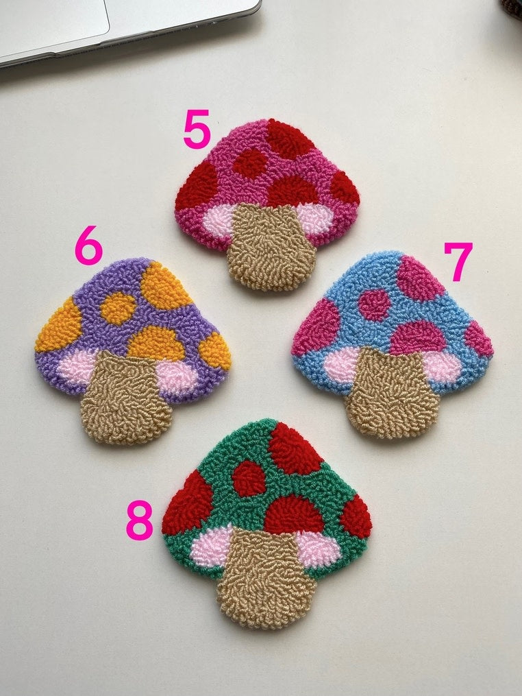 Set of colorful mushroom-shaped coasters with a textured punch needle pattern.