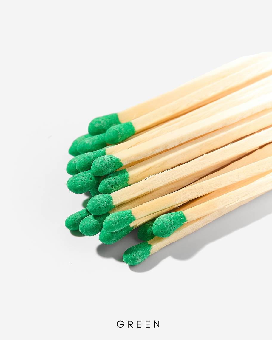 A bundle of 3-inch wooden safety matches with green tips against a white background.