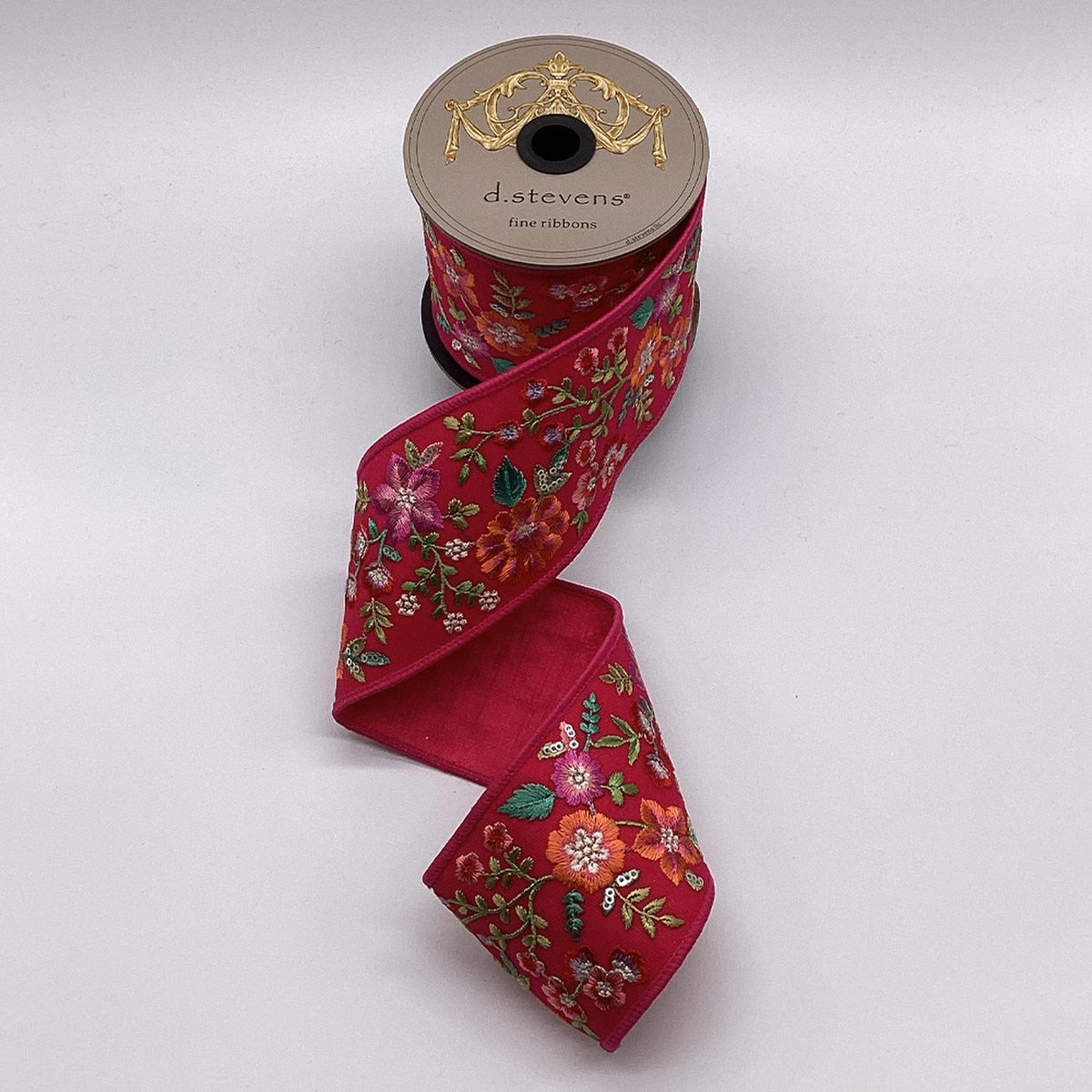 3-inch hot pink sheer ribbon with colorful floral embroidery on a spool.