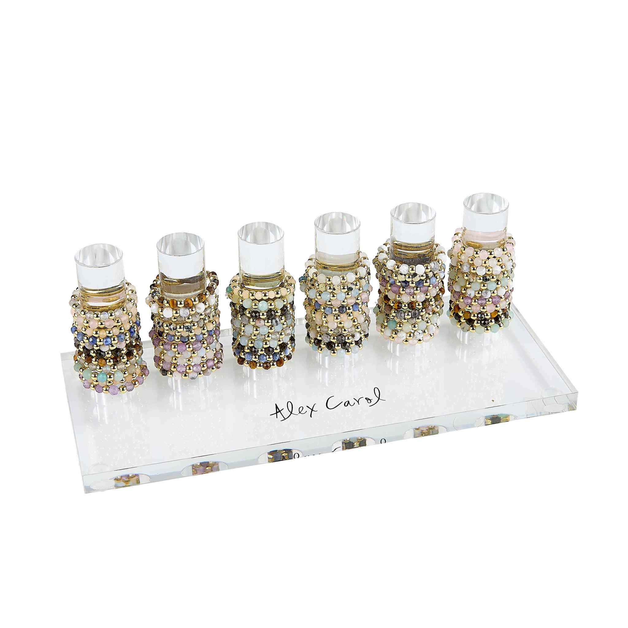 Six beaded rings with gold balls and semi-precious stones displayed on a clear acrylic stand.