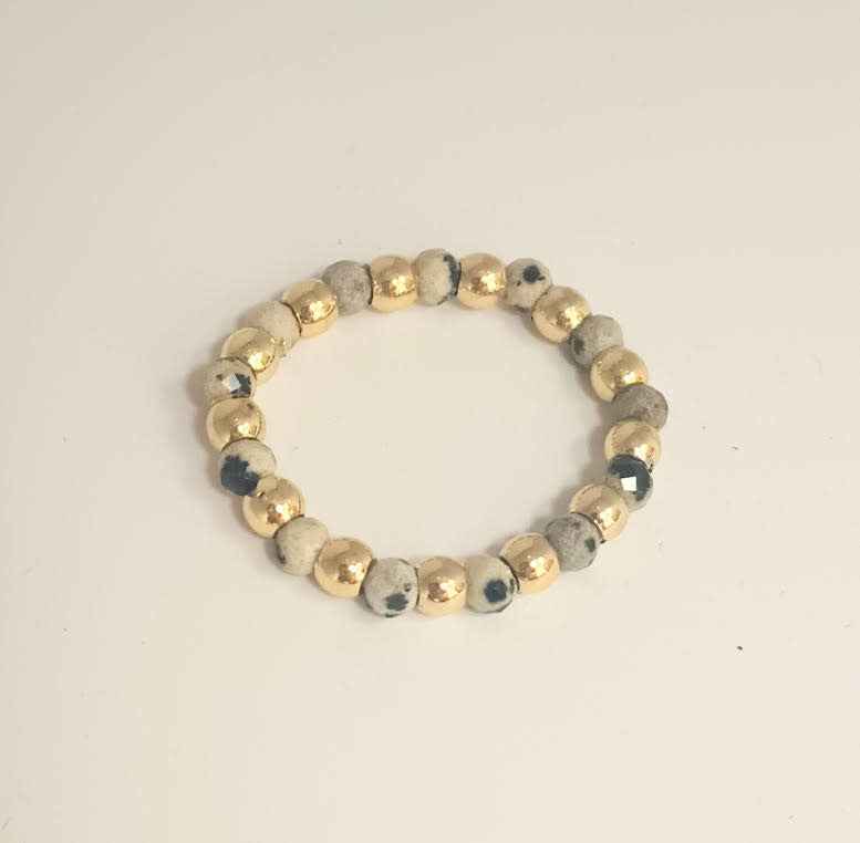 A beaded ring featuring alternating gold-tone metallic balls and speckled dalmatian jasper stones.