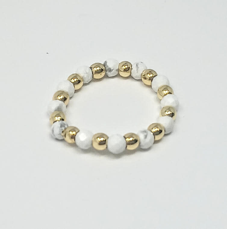 A stretch ring featuring alternating 3mm gold-tone beads and white marbled semi-precious stones.