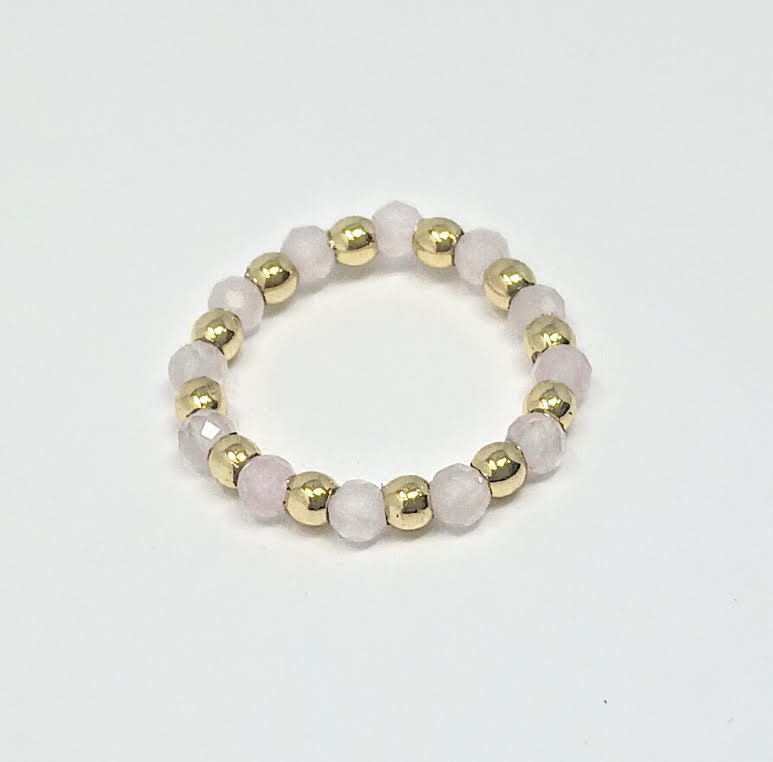A beaded ring featuring alternating gold-tone metal balls and pale pink semi-precious stone beads.