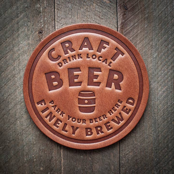 Four square leather coasters in a natural tan color with visible grain texture.