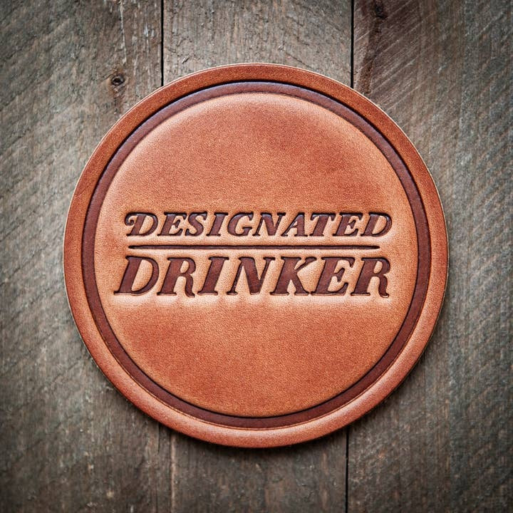 Square leather coaster with designated drinker text in a circular cutout