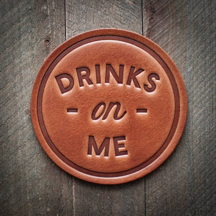 Four square brown leather coasters with a textured surface holding glasses.