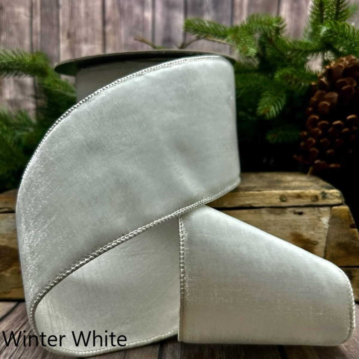 4-inch wide winter white velvet ribbon on a spool with a metallic finished edge.