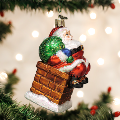 Red Santa Claus ornament with white beard standing inside a black chimney.