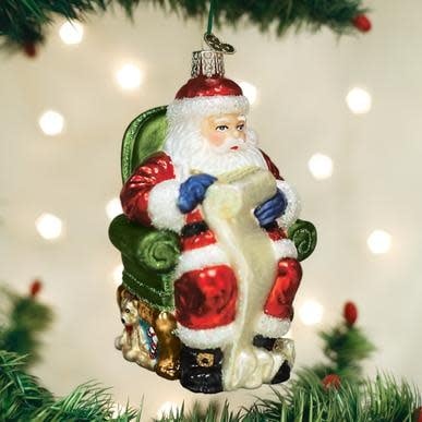 Glass Christmas ornament shaped like Santa Claus holding a list with red suit and white beard.