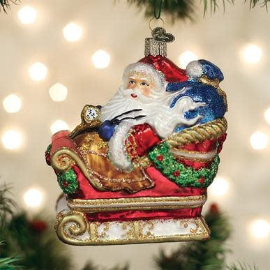 Red Santa Claus ornament in a sleigh with white beard and black boots.