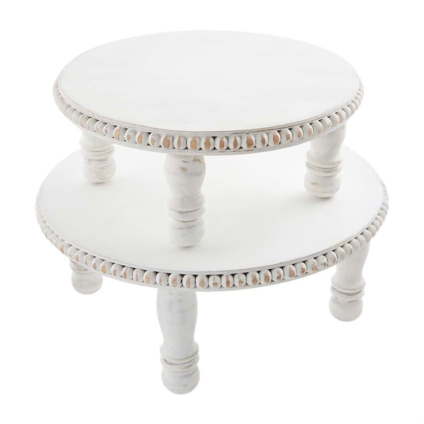 White mango wood pedestal tray with beaded rim holding spring flowers