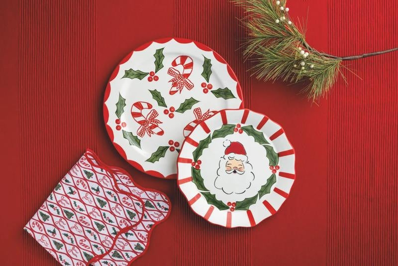 Holiday Holly ceramic platters with Santa and candy cane designs on a red tablecloth.