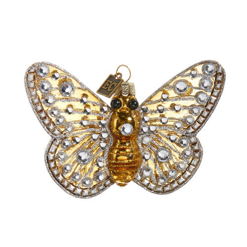 Gold resin butterfly ornament with jeweled accents hanging on a holiday tree branch.