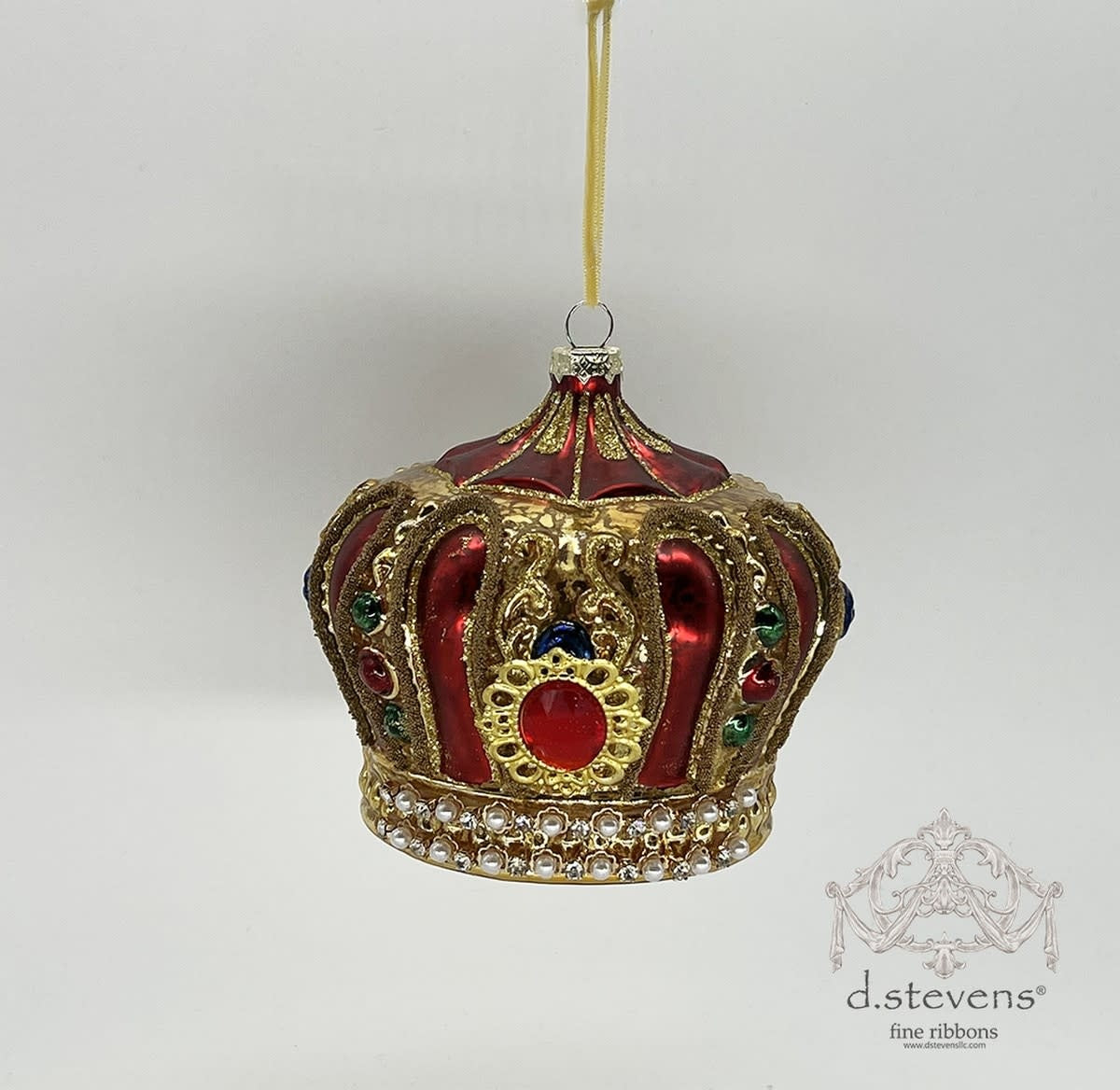 Gold glass jeweled crown ornament with sparkling clear stones on a tree branch