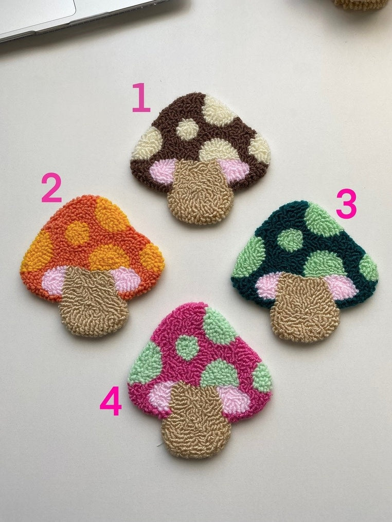 Handmade colorful mushroom-shaped punch needle coasters with a textured surface.