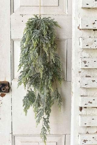27-inch artificial cedar bough hanging decoration with realistic green foliage on a white door.