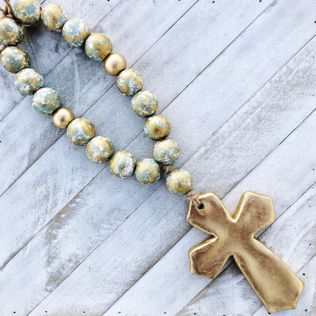 Handmade clay cross with gold enamel blessing beads hanging from a doorknob.
