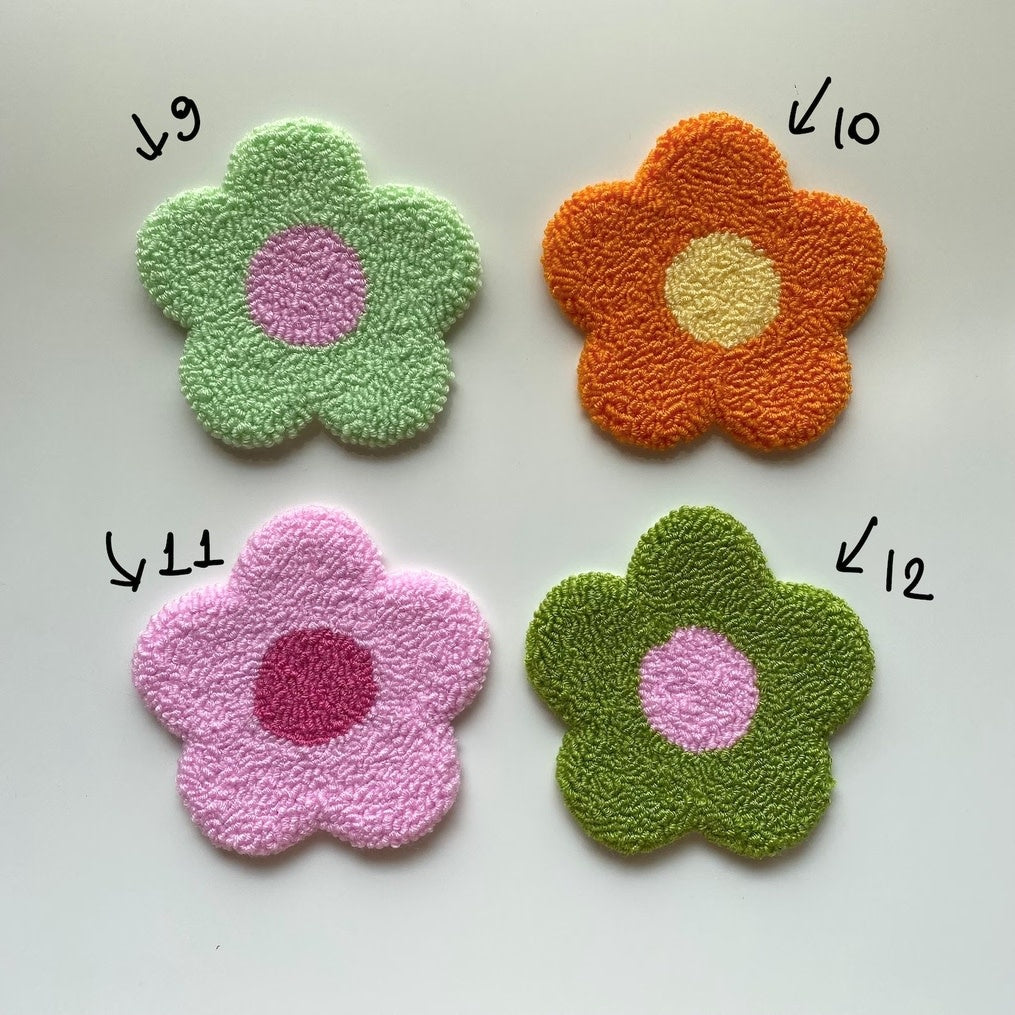 Handmade punch needle coaster with geometric patterns in earth tones on a circular silhouette.