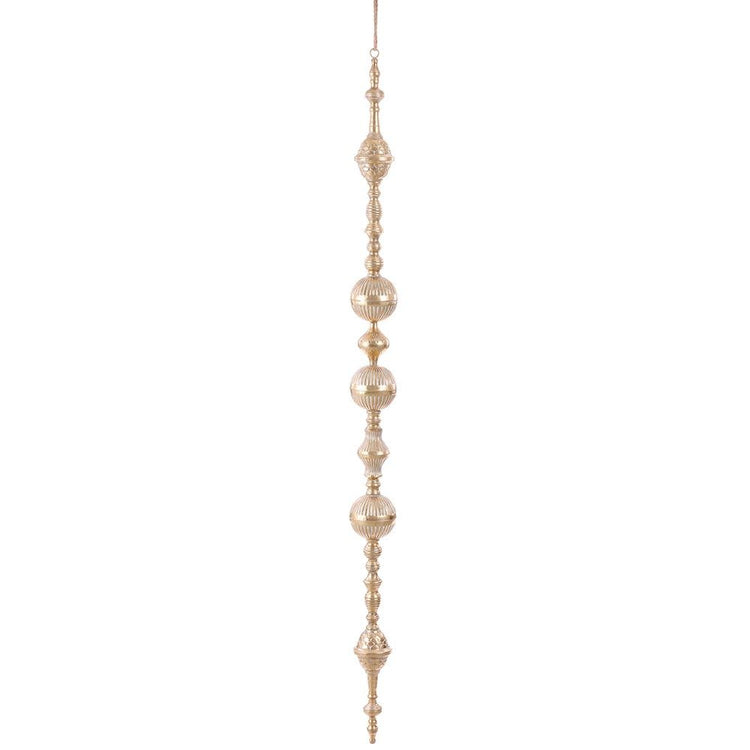 Gold metal finial ornament with rope accents hanging from a tree branch