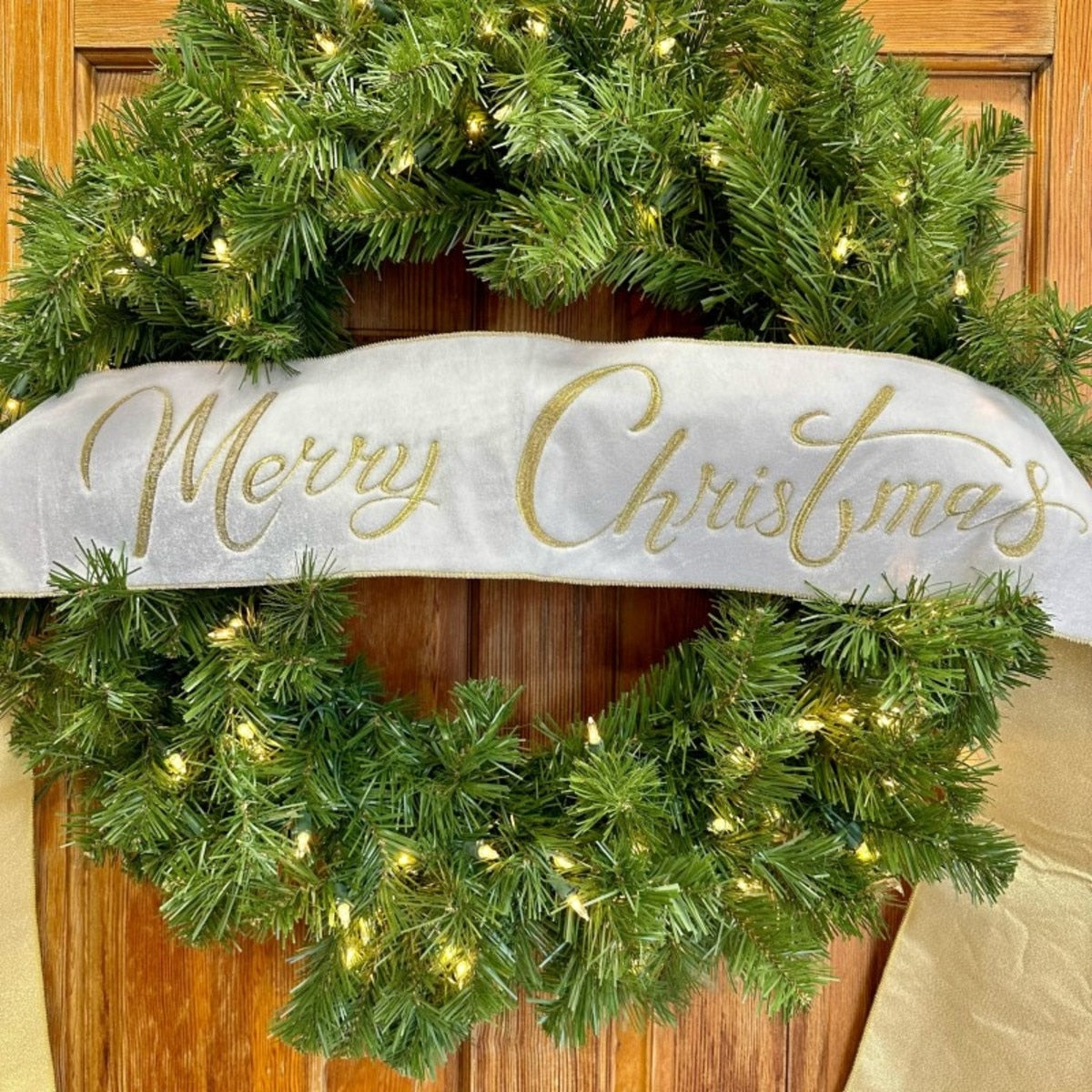 Winter white velvet wired banner with gold embroidered Merry Christmas on a lit evergreen wreath.