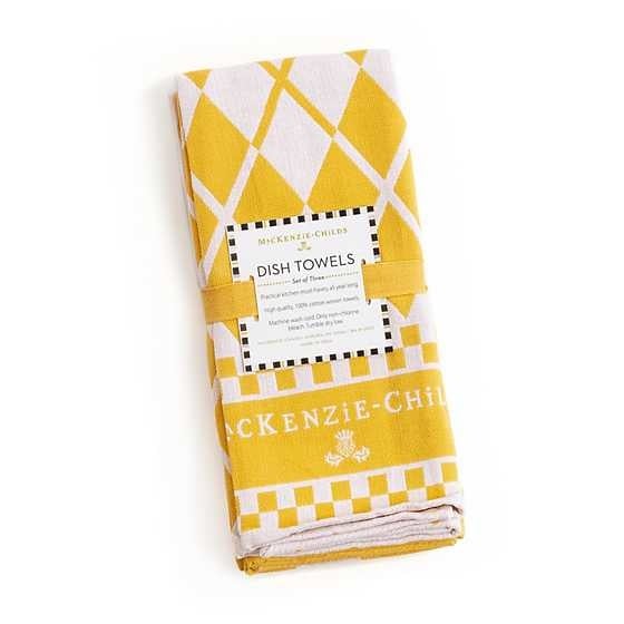 Three yellow cotton dish towels with white argyle patterns and a logo hanging from hooks.