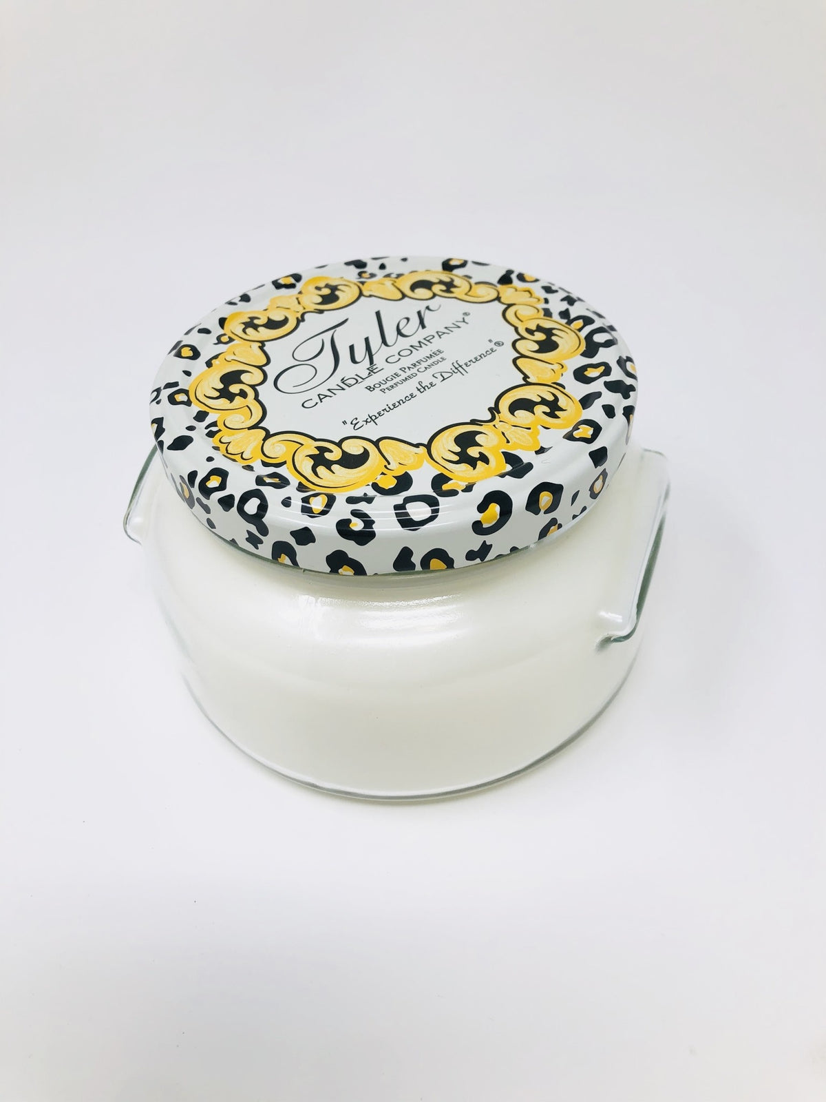A large white jar candle with a black wick labeled Tyler Candle.