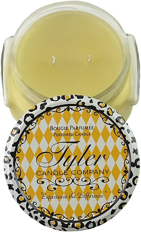 A clear glass jar containing a white candle with the label Tyler Candle.