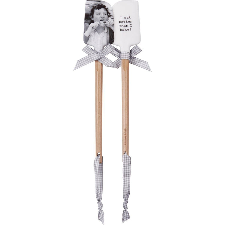 Double-sided silicone spatula with wooden handle; one side shows vintage photo print, other has 'I Eat Better Than I Bake' text and gray-white gingham bow.