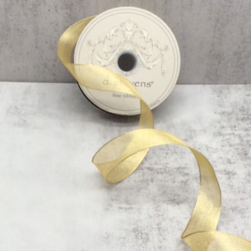 7/8 inch gold metallic mesh ribbon unspooled on a grey textured surface.