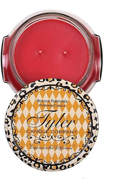 A black glass jar containing a white candle with the label Tyler Candle.