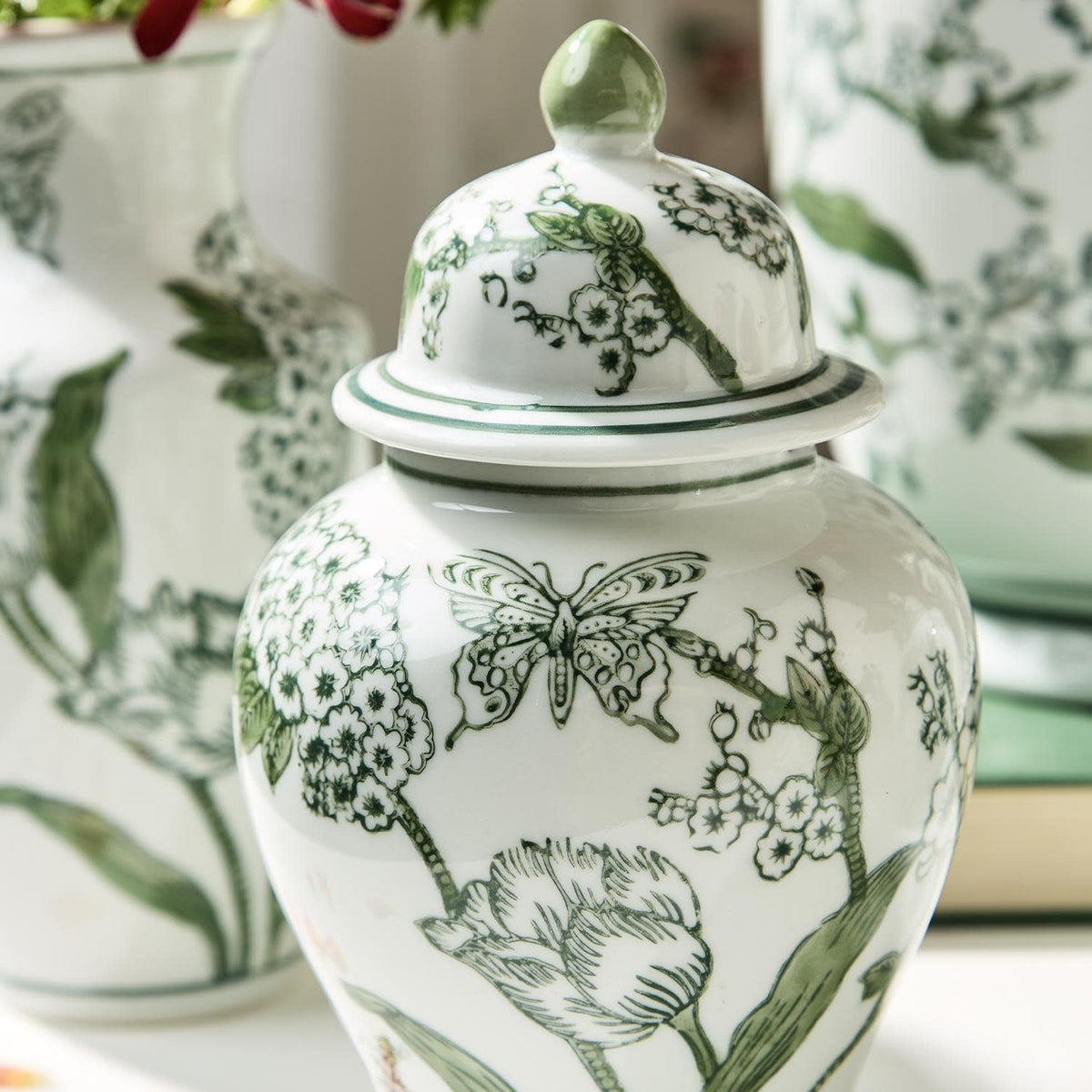 Hand-painted green and white porcelain jar with lid featuring primrose and lotus chinoiserie floral pattern.