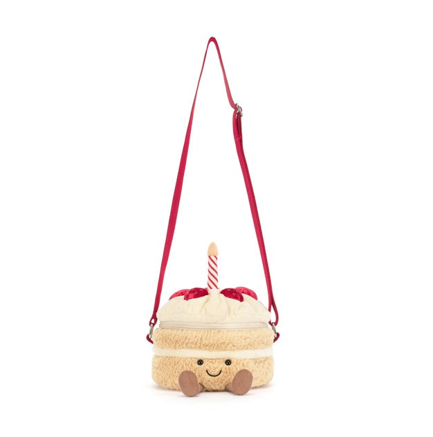 Plush birthday cake bag with a smiling face, candle, and red shoulder strap.
