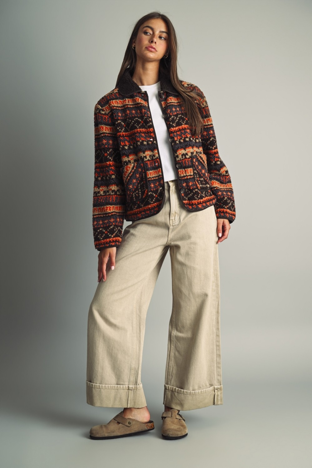 Woman in a Camila ethnic patterned teddy fleece jacket, white tee, and beige wide-leg pants.