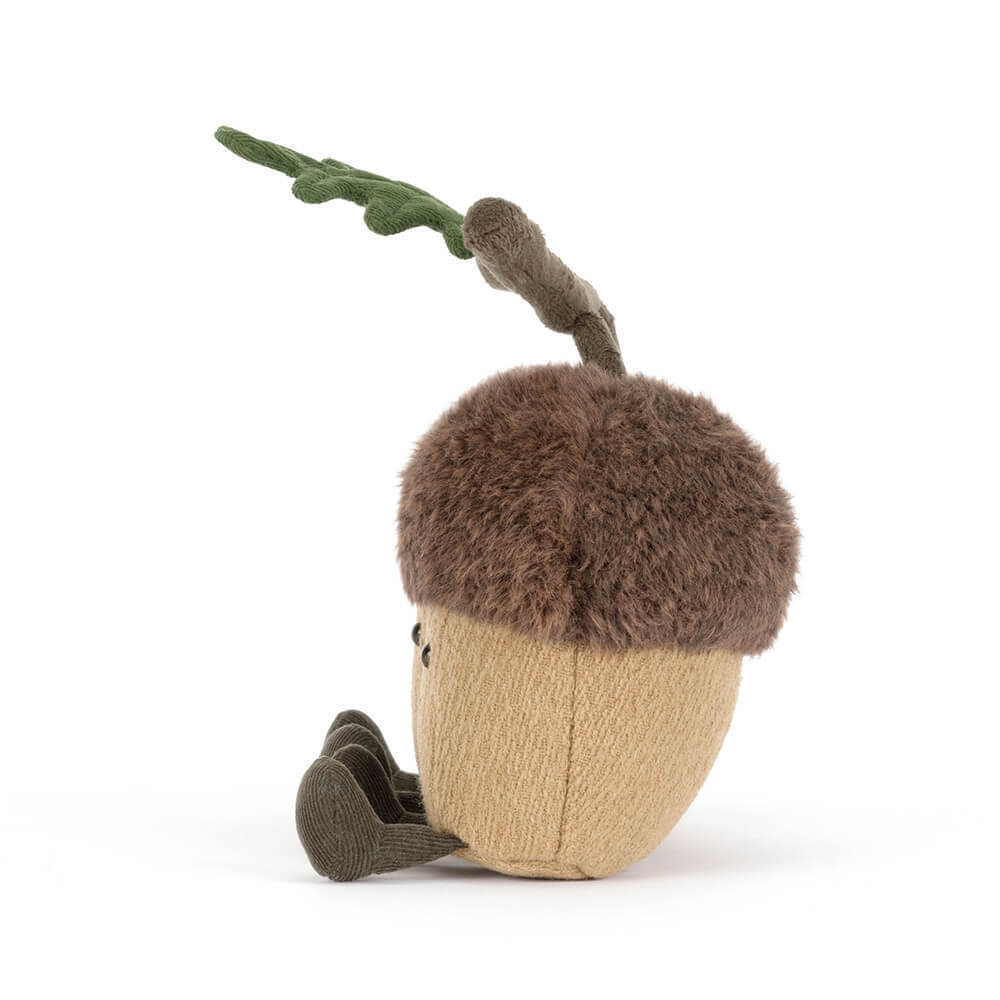 Side view of a plush acorn toy with a fuzzy brown cap, tan body, corduroy legs, and a green leaf.