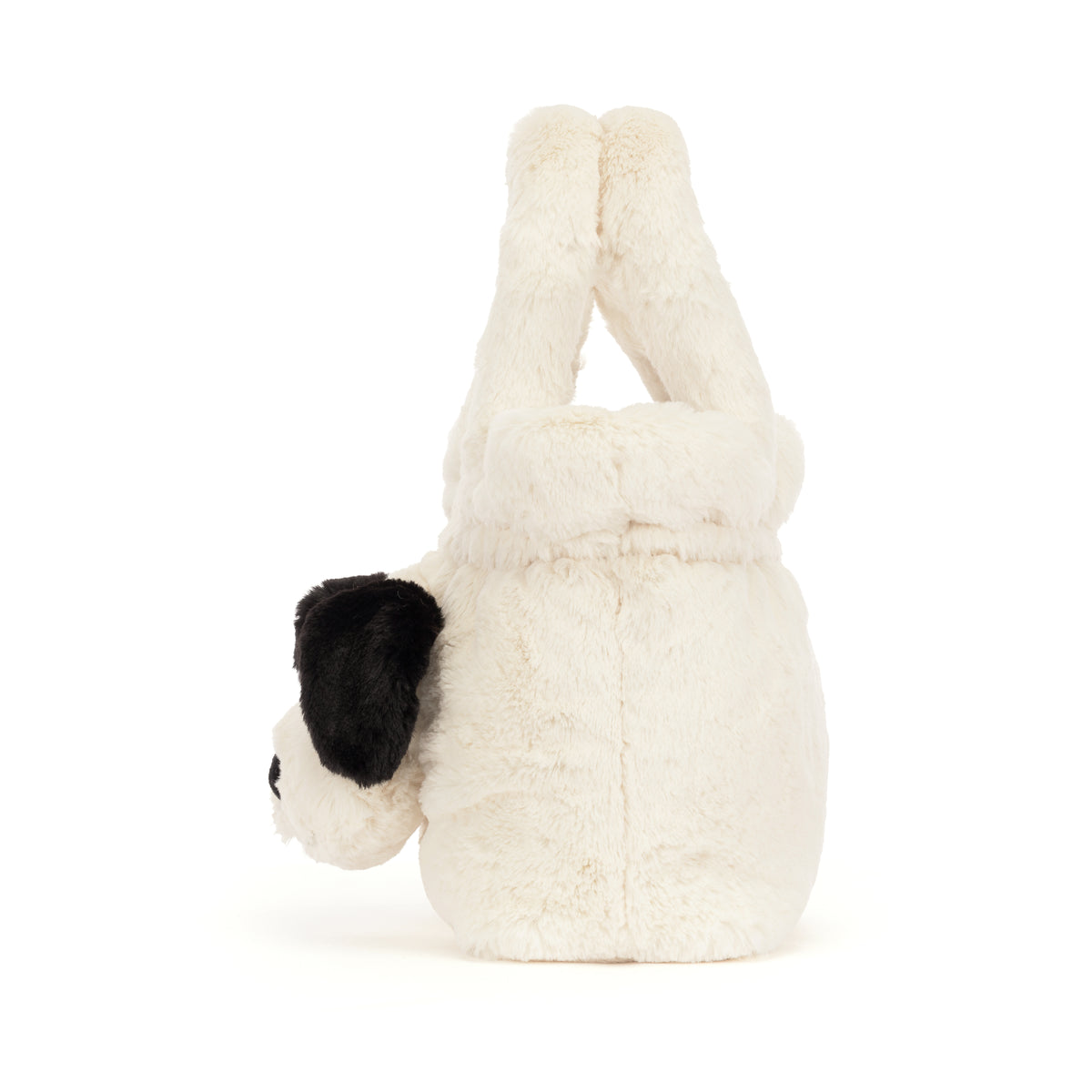 Side view of a white plush puppy handbag with a black ear and two soft top handles.