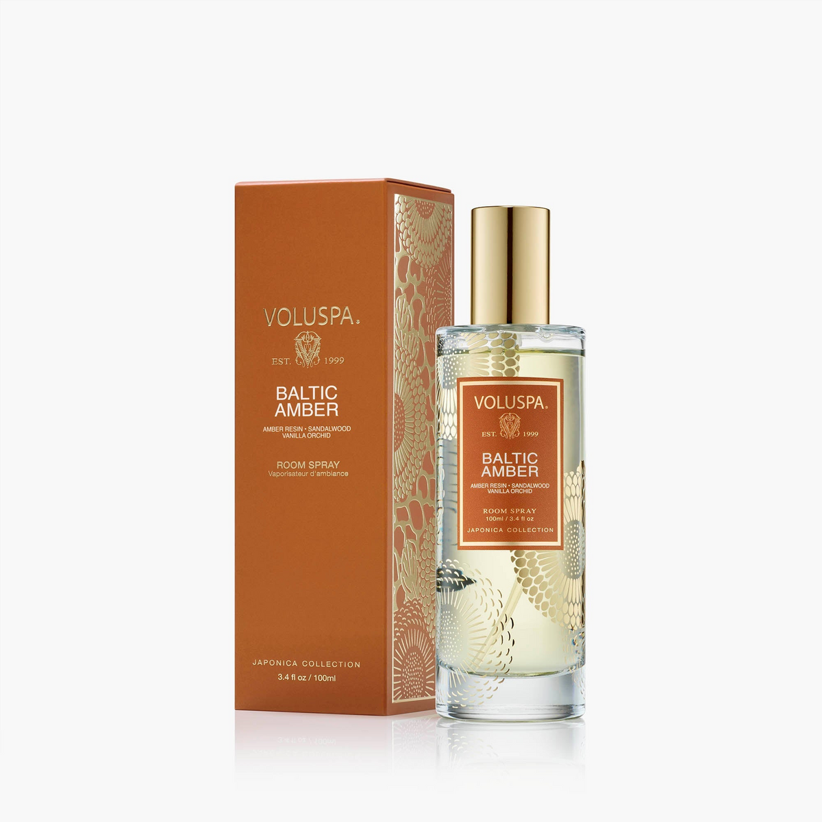 Baltic Amber Room Spray in a glass bottle with gold cap next to its orange and gold patterned box.