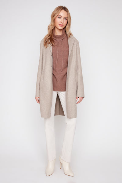 Woman wearing a heather latte brushed knit long coat with raw edges over a brown turtleneck.