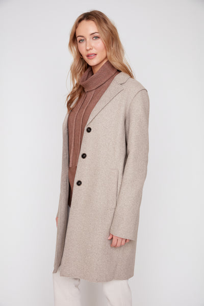 Woman wearing a heather latte brushed knit long coat with raw edges over a brown turtleneck.