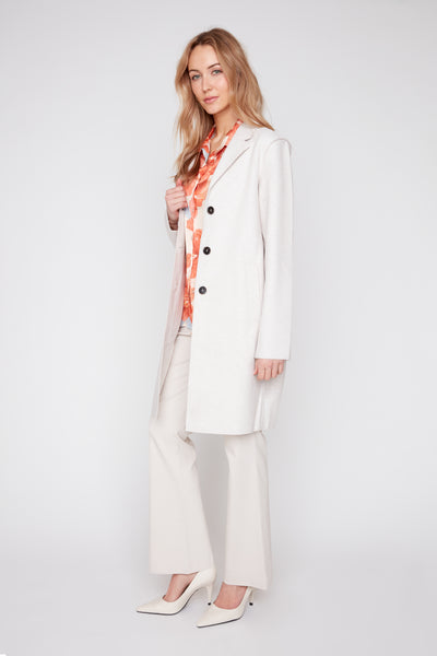 Woman wearing a long oatmeal-colored brushed knit coat with raw edges and dark buttons.