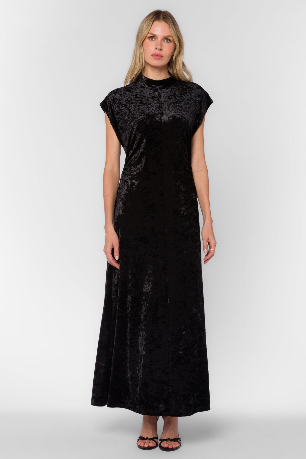 Woman wearing the Callie Dress, a black velvet maxi dress with a mock neck and cap sleeves.