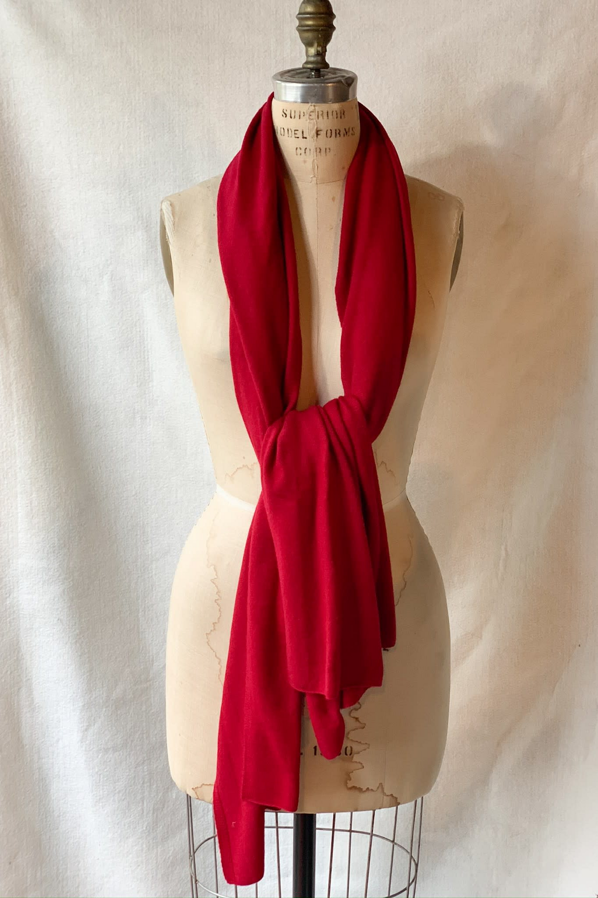 Red cashmere solid scarf draped and knotted on a vintage dress form mannequin.