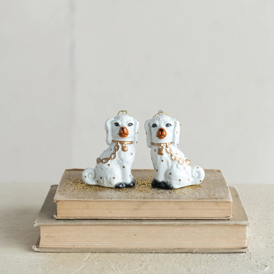 White ceramic Staffordshire dog ornament with gold accents sitting on vintage books.