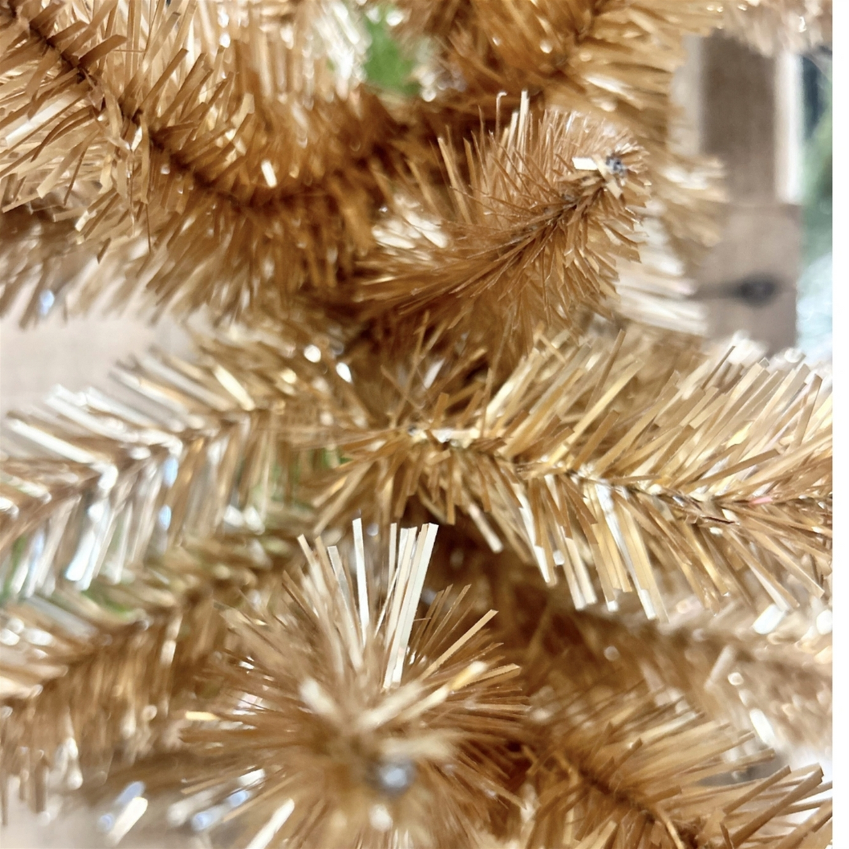 Close-up of shimmering champagne tinsel garland with dense, metallic needles.
