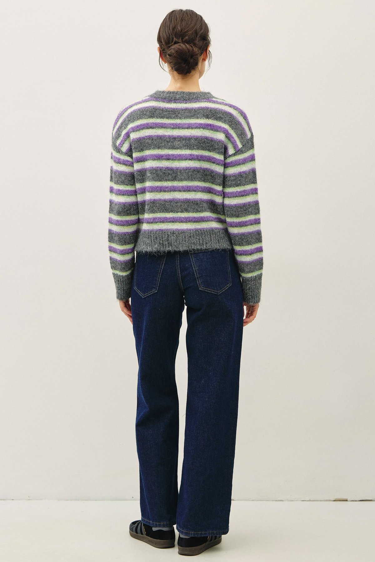 Back view of a woman wearing the Chloe Striped Button Up Cardigan in charcoal with blue jeans.