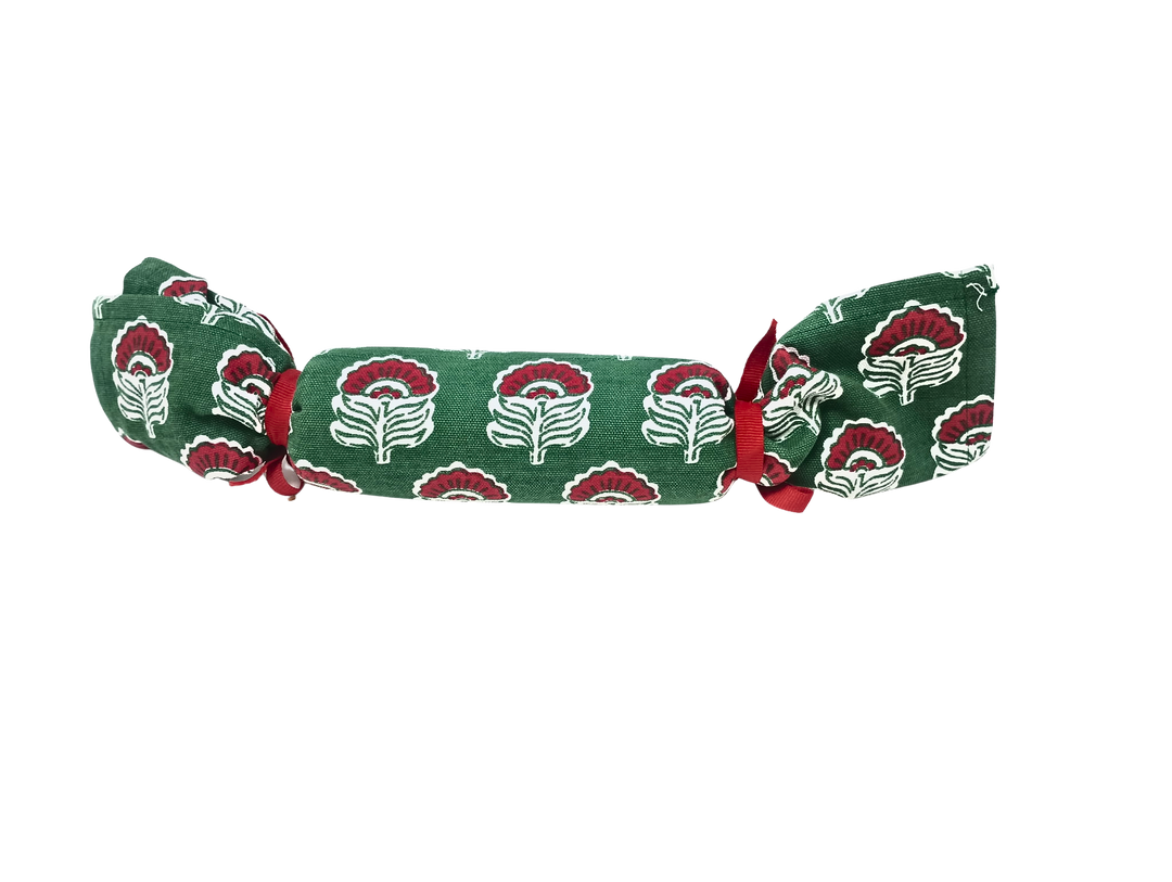 Green Christmas block print towel rolled and tied with red ribbons in a cracker shape.