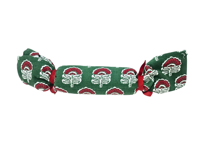 Green Christmas block print towel rolled and tied with red ribbons in a cracker shape.
