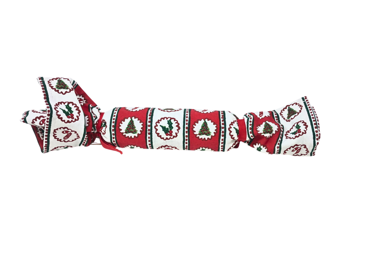 Christmas block print towel rolled and tied with red ribbon, featuring holly and tree patterns.