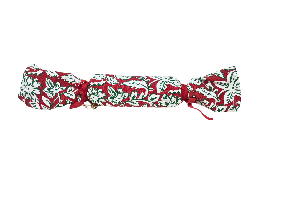 Red and white floral block print cotton towel rolled and tied like a Christmas cracker.
