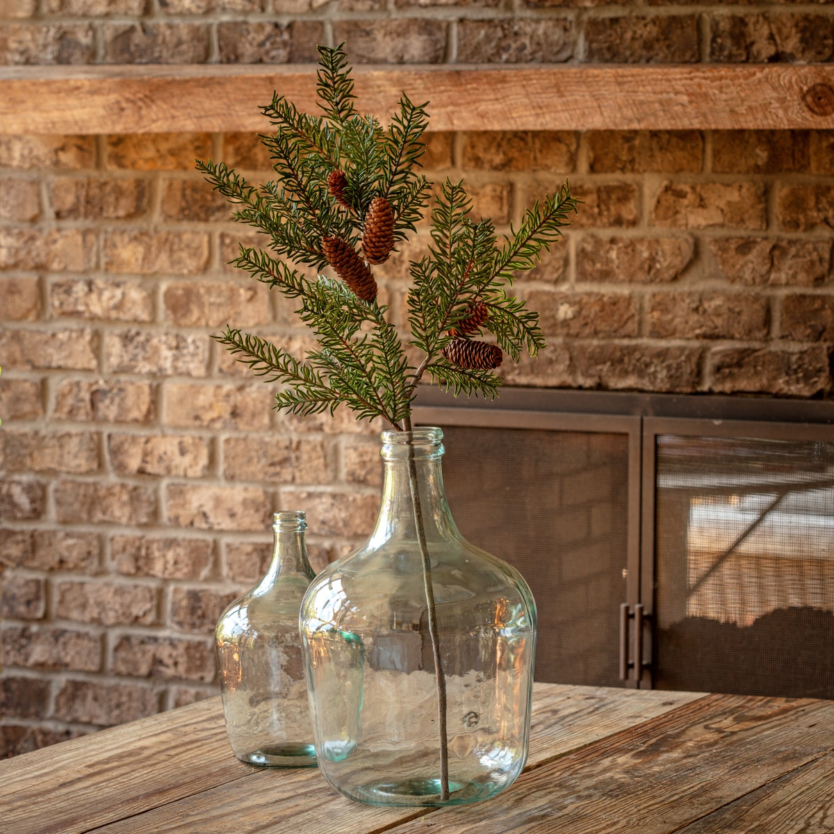 A 38.5-inch artificial Douglas Fir branch with green foliage and pinecones in a clear glass jug.