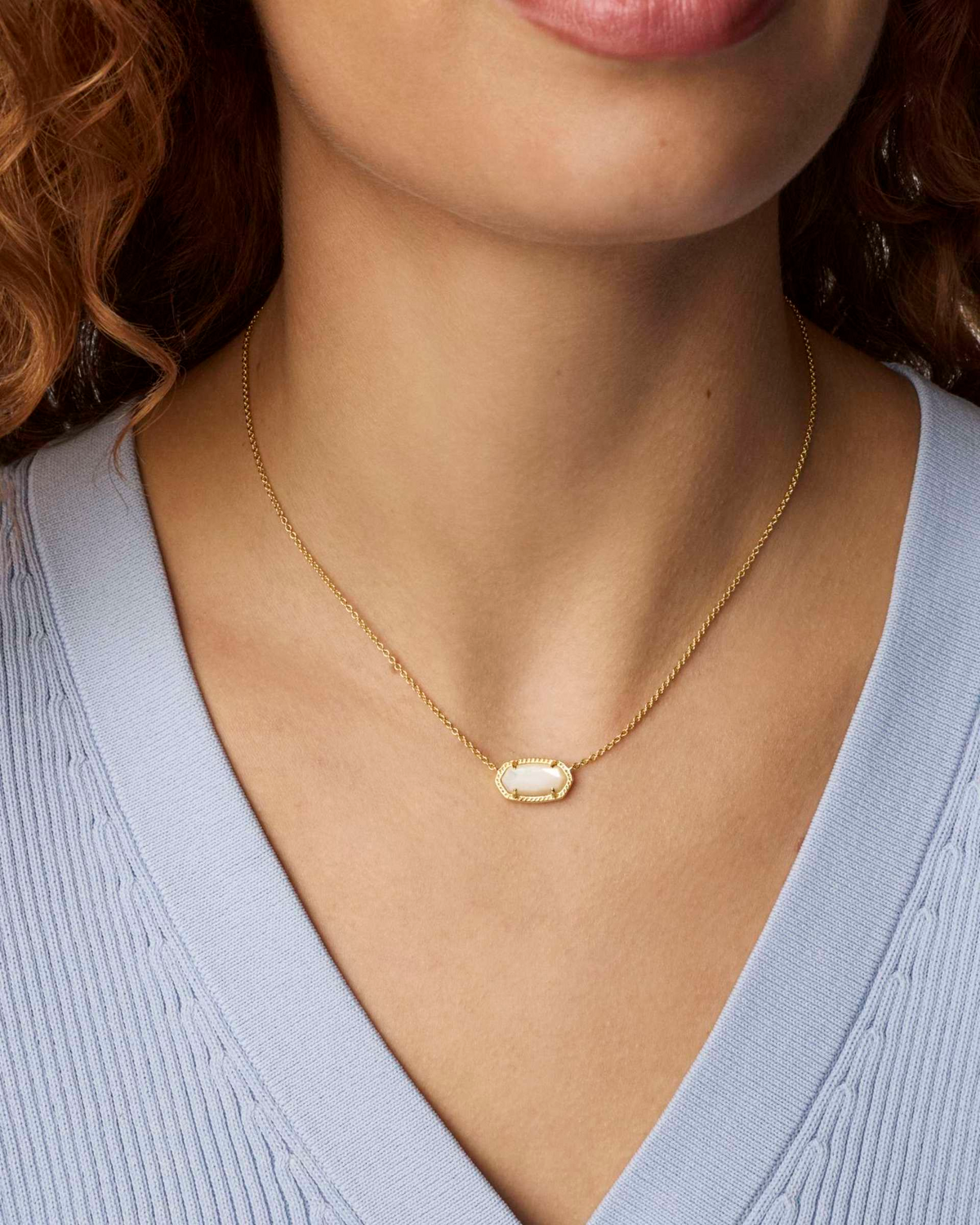 Woman wearing the Elisa Short Pendant Necklace in gold with an oval white stone.